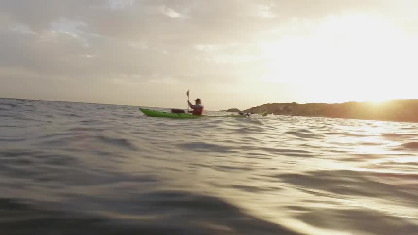 Two kayaks are paddling out into the ocean