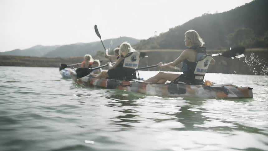 A group of people are rowing kayaks on a river during the day
