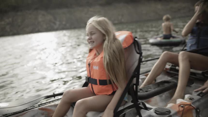 A little girl smiles as she rocks a canoe on a river during the day