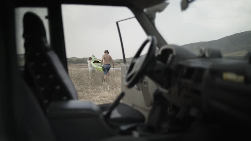 Two people carry a canoe away from a car
