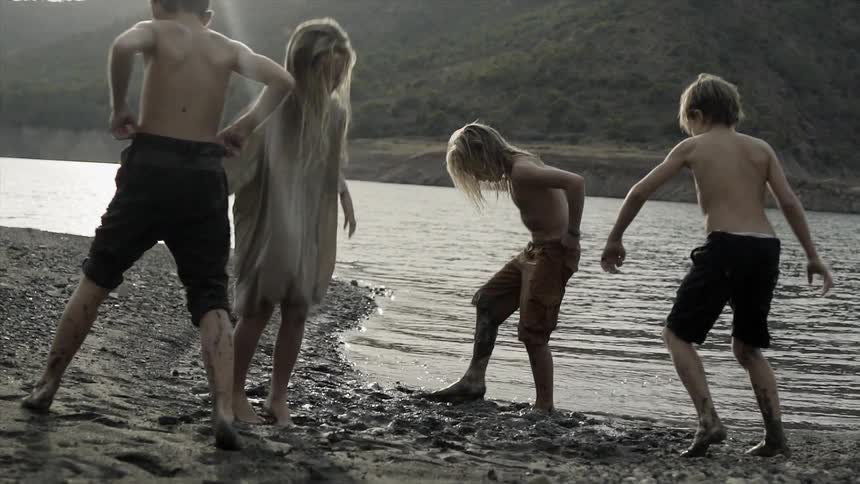 Young children play in the water and mud