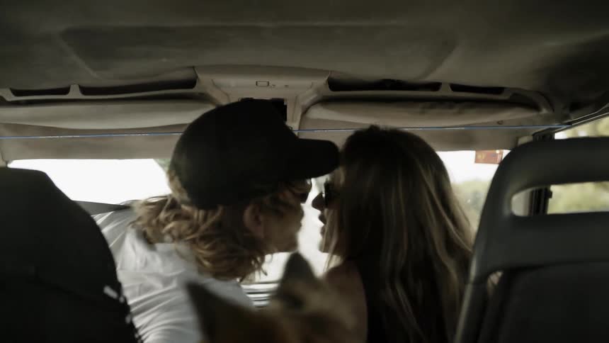 Man woman and dog ride in a vehicle and man kisses woman