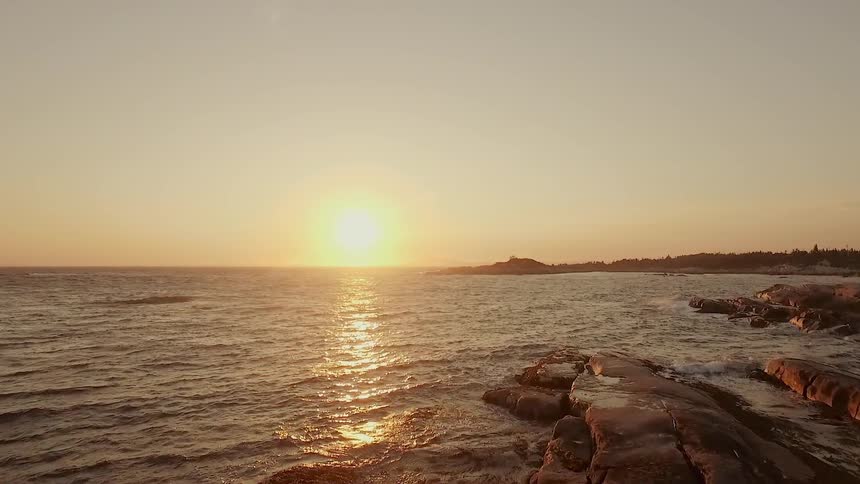 The sun is sitting over the ocean
