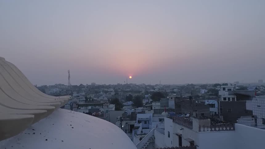 The sun is rising over a city filled with old buildings