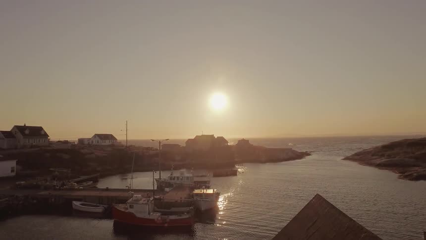 The sun sets over docked boats on the coast