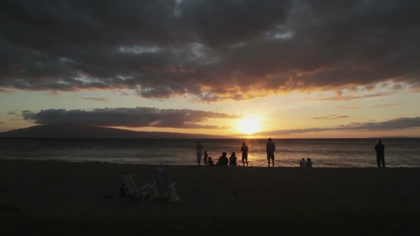 A group of family and friends on the beach at sunset