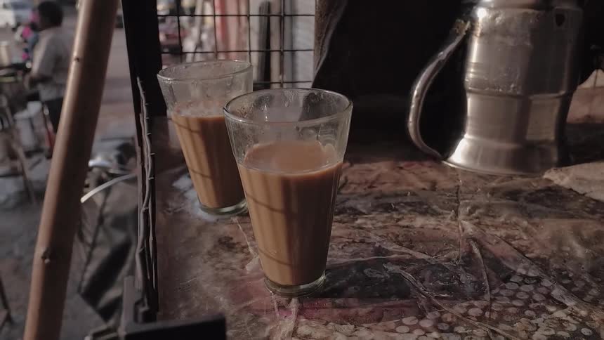 Two glasses with hot coffee in them are sitting on a table on a balcony