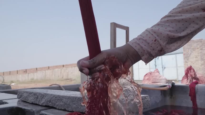 Someone is washing red dye from a rag