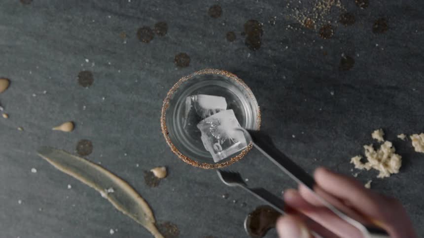 Person putting ice in glass with tongs
