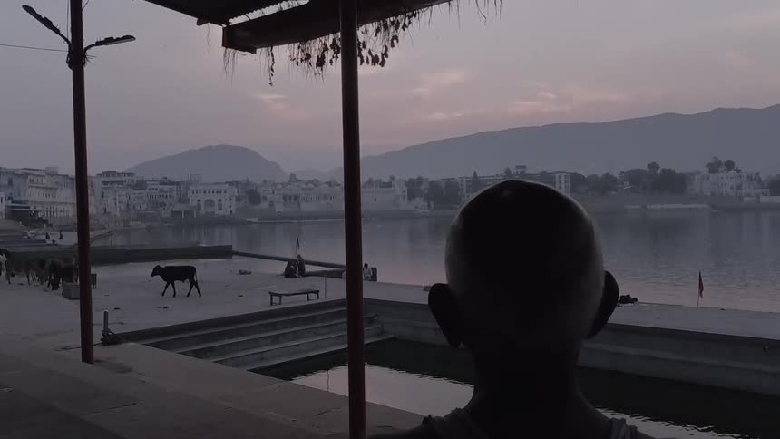 A man is standing looking across a river at dusk