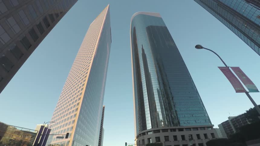 Traveling along a city street, looking upwards at skyscrapers
