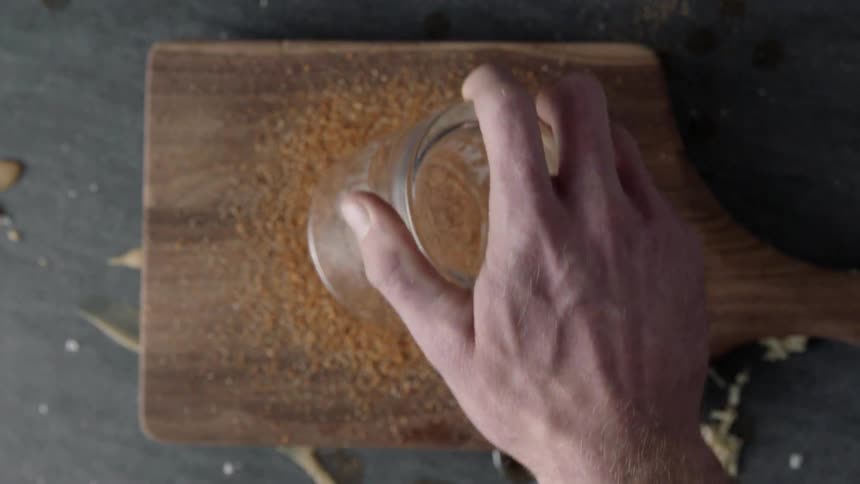 A person rolls a cup in crumbs