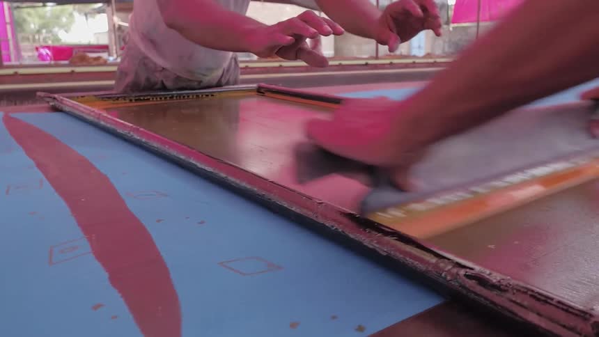 Workers are screen-printing fabric during the day