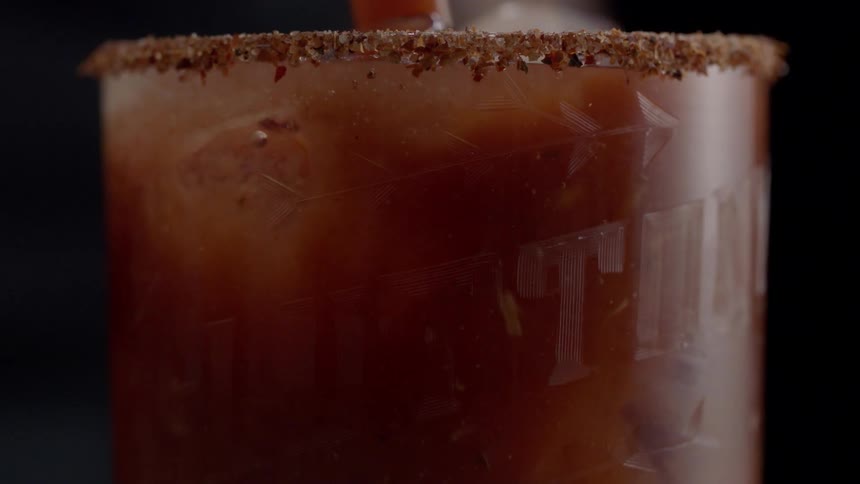 A glass is getting a red liquid poured into a clear liquid