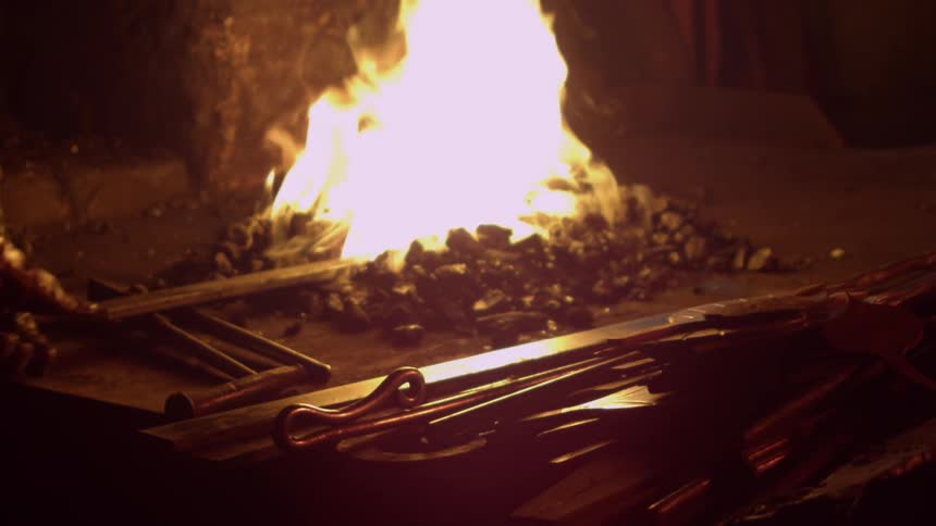 A man uses a stick to rage a campfire