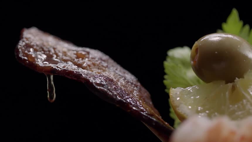 A piece of bacon drops grease hanging out of a drink