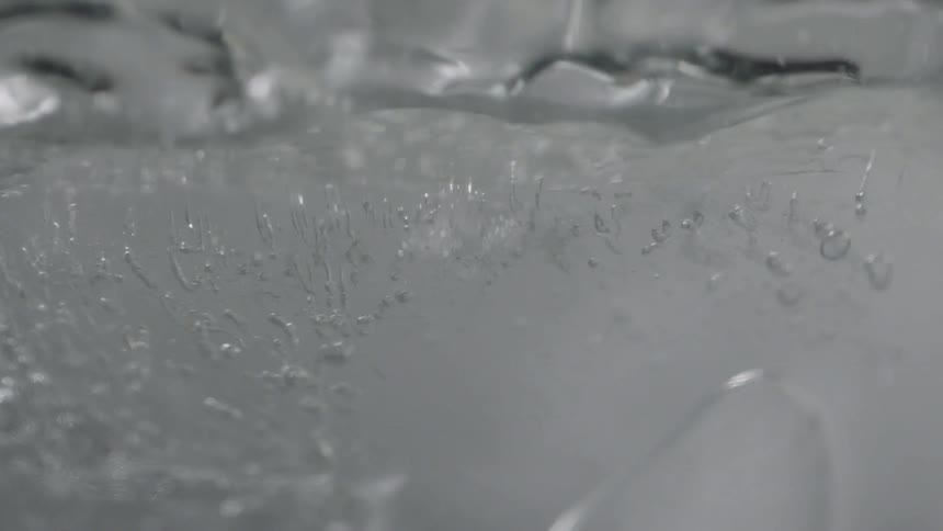 The water is flowing around the ice in the glass