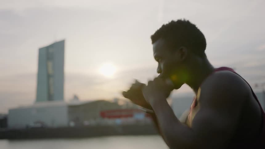 A man is shadow boxing by the water