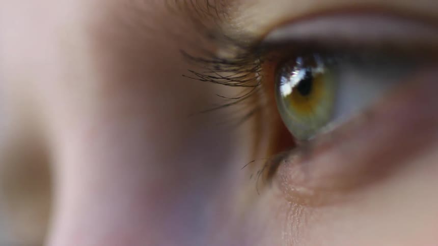 A close up of a lady with green eyes blinking