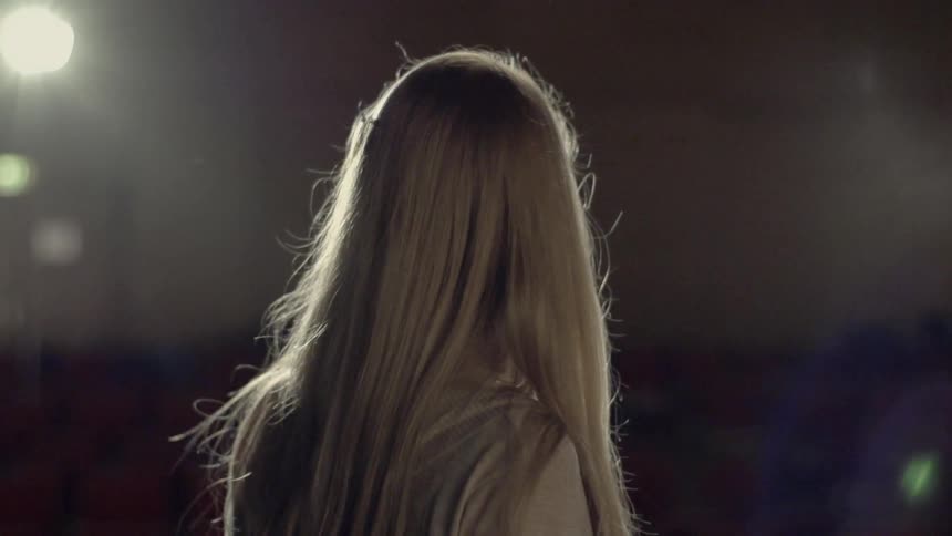 A woman walks towards spotlights