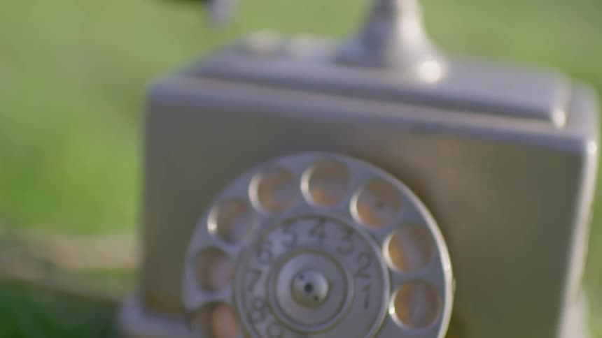 An old style telephone is sitting in the grass