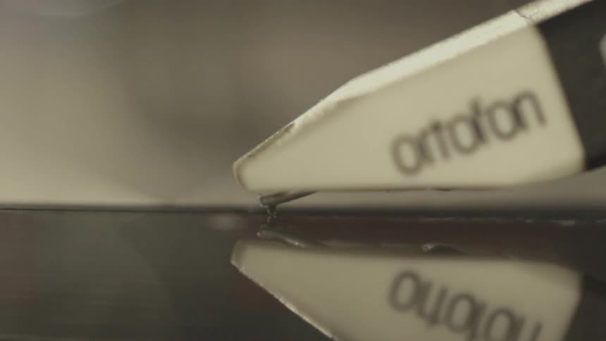 A record needle is gliding over the record before lifting