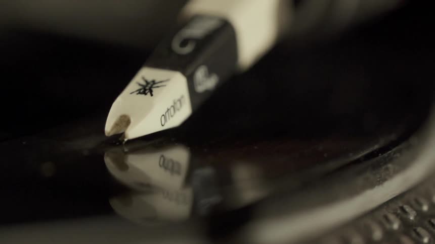 A record player needle is dropping down and making contact with the record