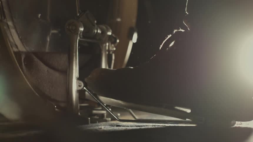 A drummer is pressing the pedal on his bass drum