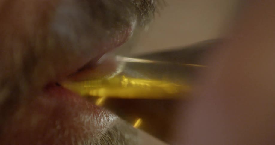 Man with a beard places a glass of beer to his lips