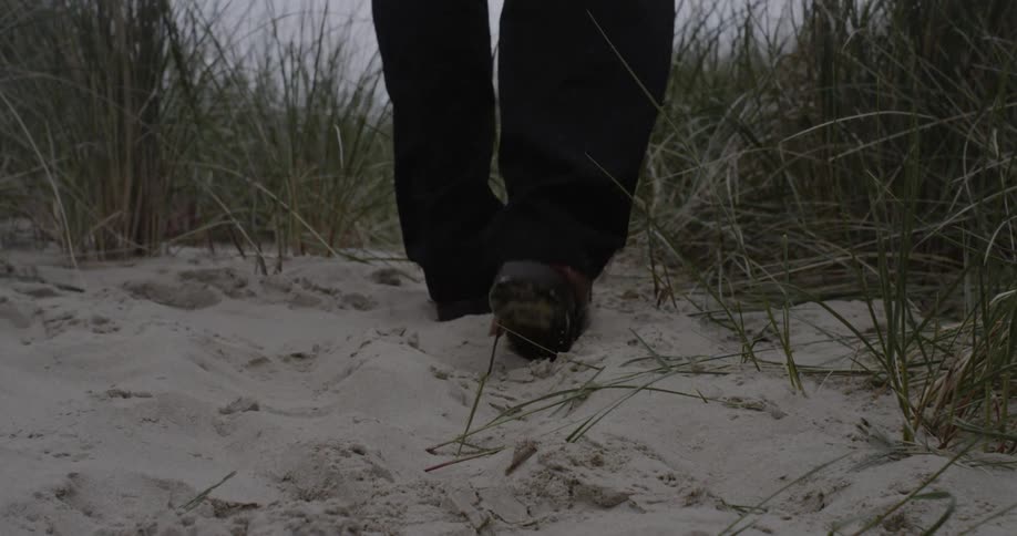 Man walks through sand and grass