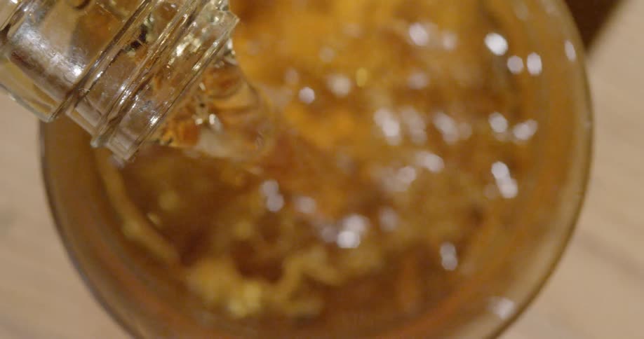 Whiskey is being poured into a glass with ice cubes