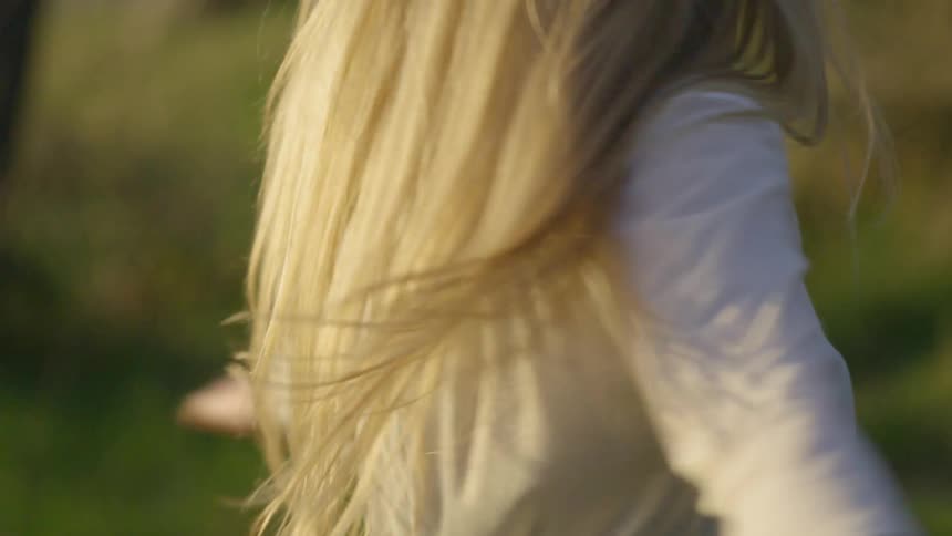 A girl twirls under the bright sun