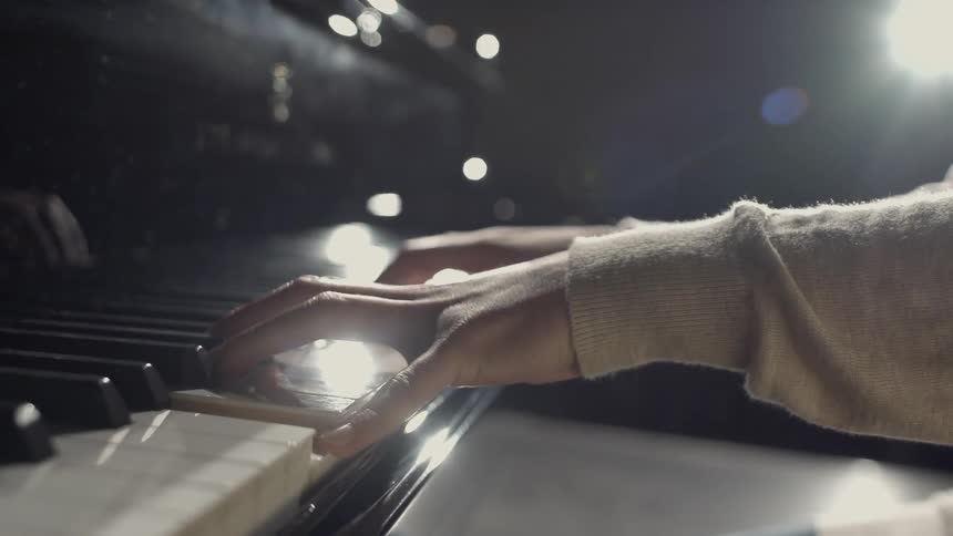 A person is playing a piano on a stage
