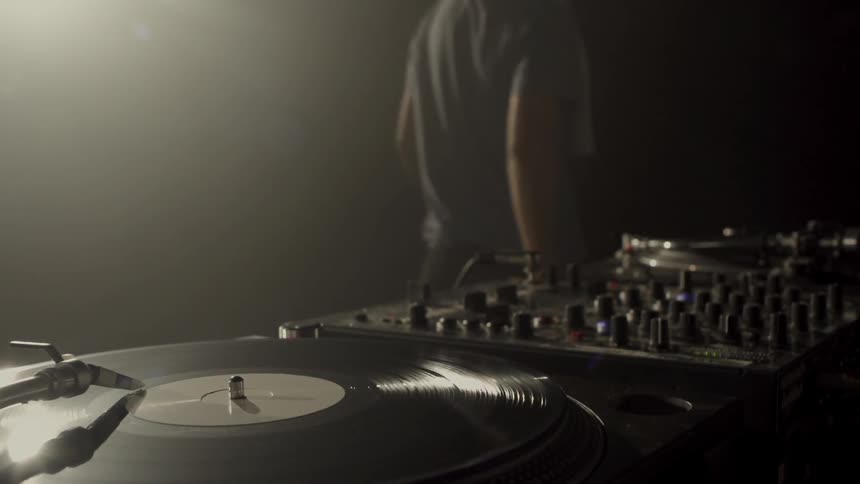 A musician walks away from turntables and mixers