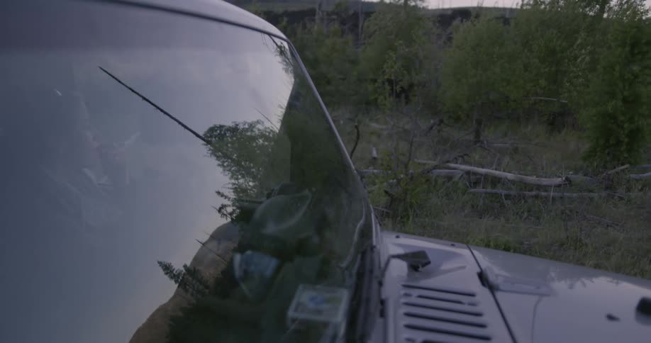 A man is driving a jeep in a natural setting at dusk