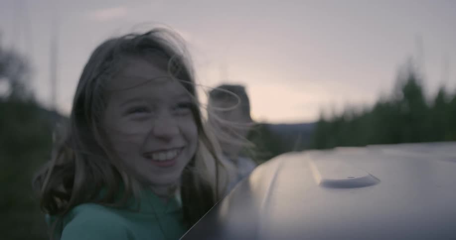 Girl and boy ride on the outside of a car