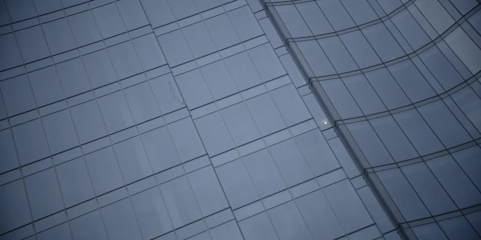 A glass building is filmed from street level