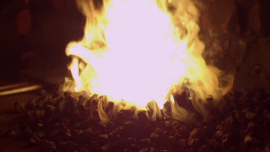 A large fire burns in an indoor fire pit