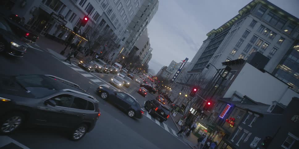 The cars make turns and people cross the street in this city