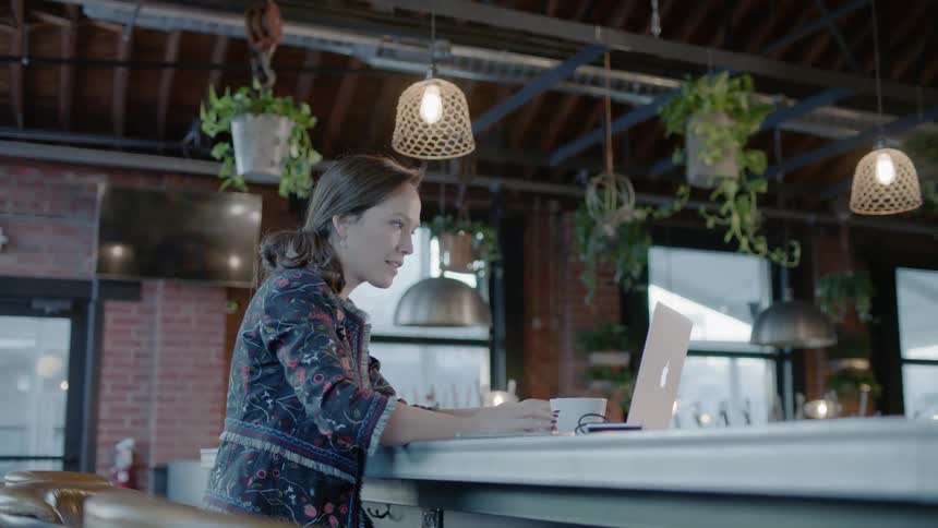 Woman opens a laptop while sitting in a coffeehouse