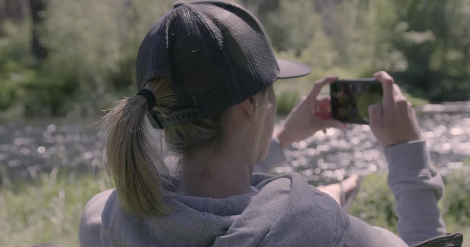 A woman takes a photograph of a stream