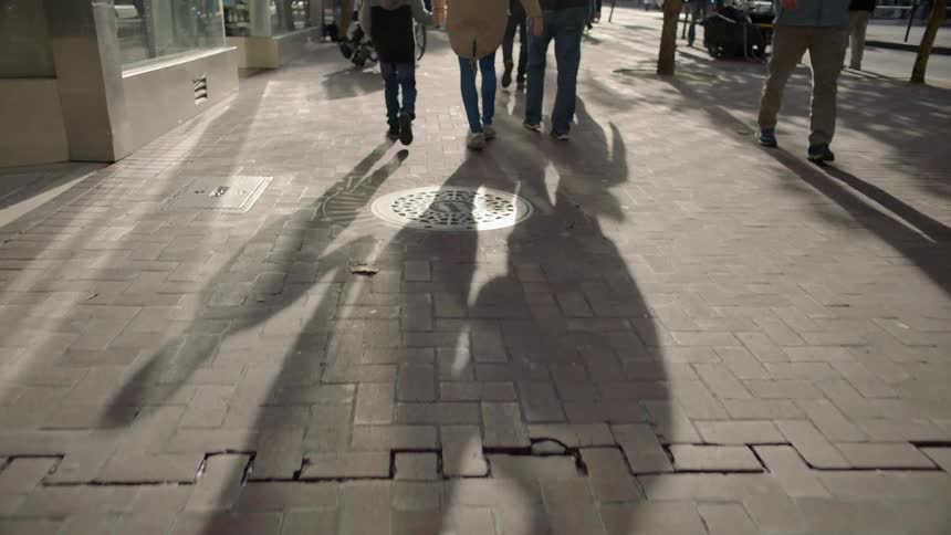 Pedestrians walk on a city sidewalk