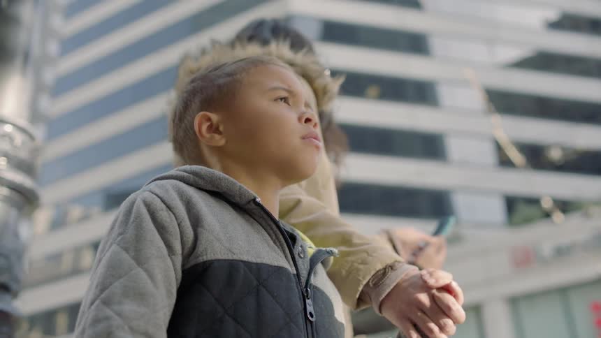 A woman is holding the hand of a little boy in the middle of the city