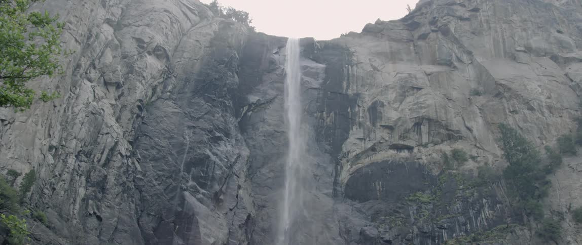 Water falls off the side of a stone mountain
