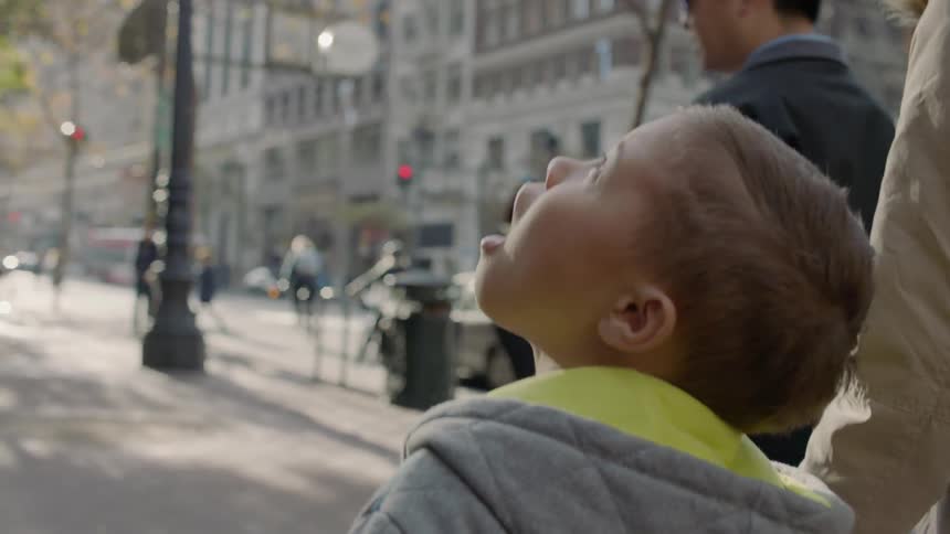 Boy holding his mother's hand looks up into the sky