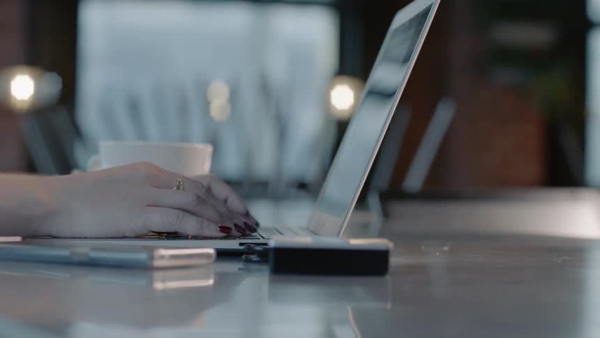 A woman types onto a laptop