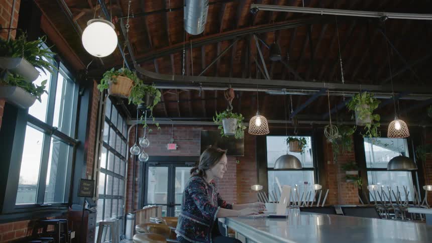 A woman is sitting at a long table drinking coffee