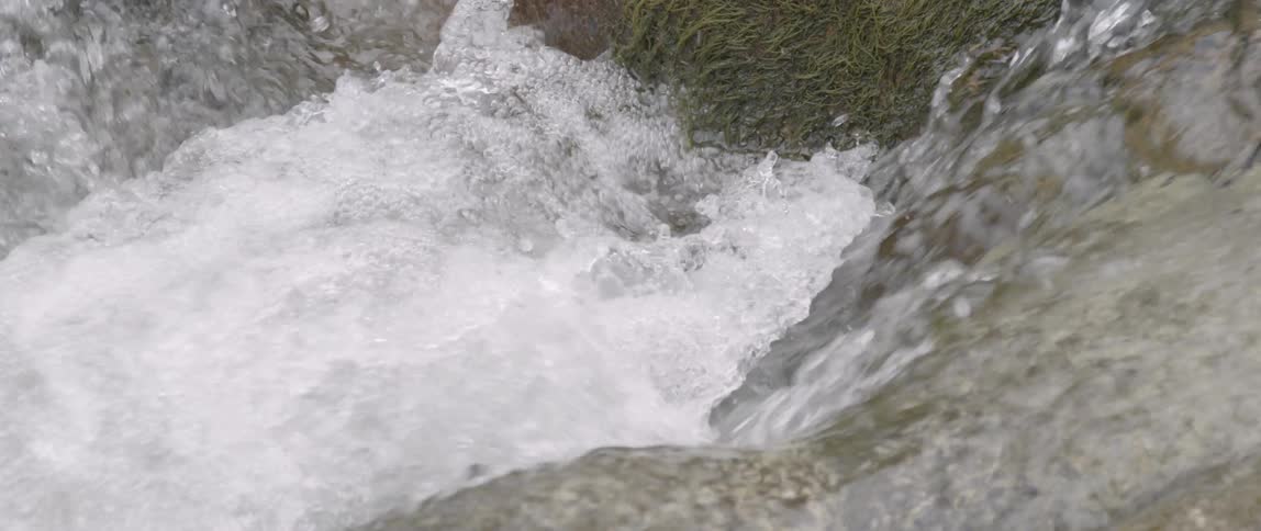 Clear water running down some rocks and splashing together