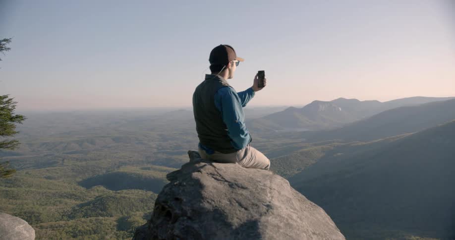 A man takes a picture on a ledge