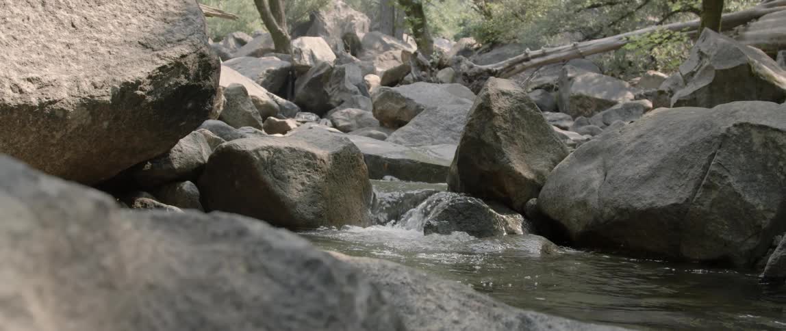Water in a stream is trickling over rocks and boulders